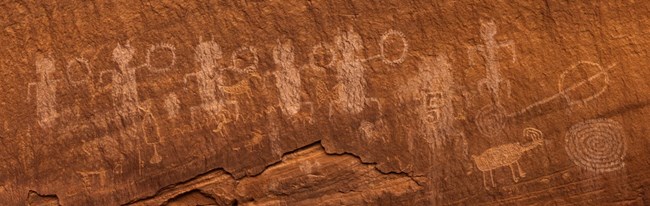 Petroglyphs carved into red sandstone wall at Natural Bridges National Monument.
