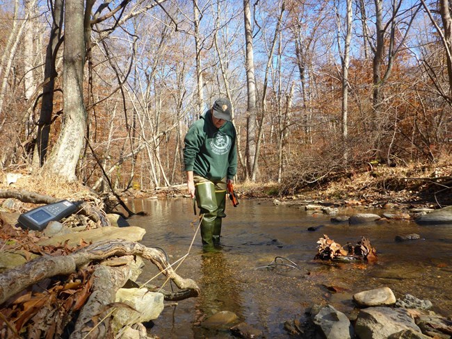 Person standing in creek with water quality monitoring gear
