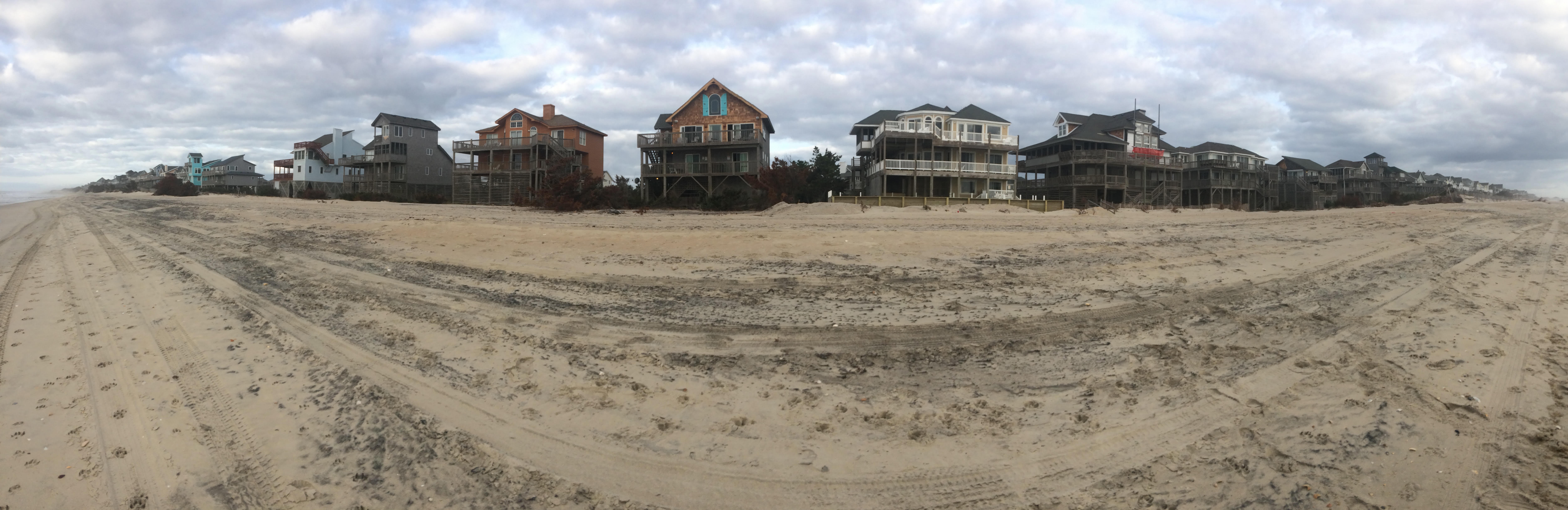 Beach houses on stilts lined up along the beach
