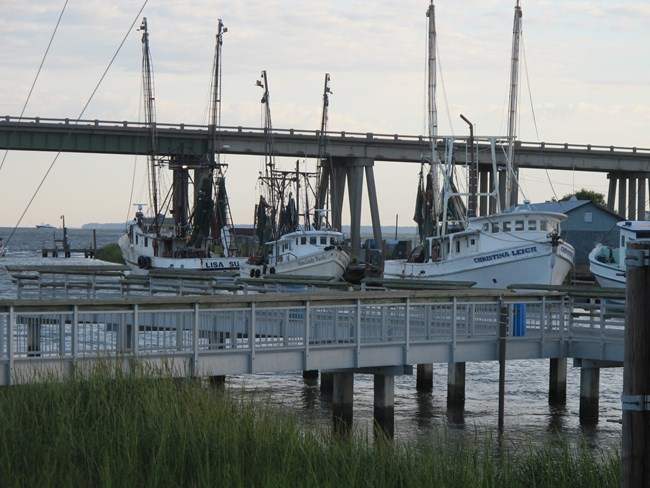 Walkway to the creek with docked boats and a large bridge in the background