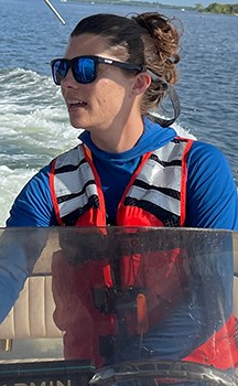 Woman in sunglasses and life vest driving a boat