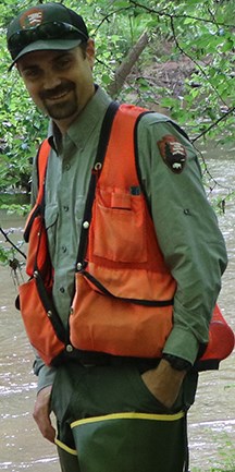 Man wearing orange vest standing in a stream