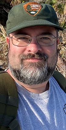 Man in beard, glasses and hay smiling for camera