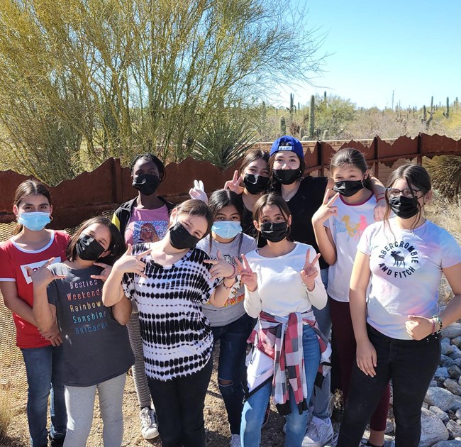 Diverse group of preteen girls in face coverings pose in DRLC courtyard.