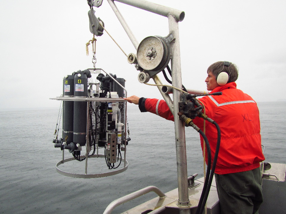 Person lowering CTD instrument into Glacier Bay