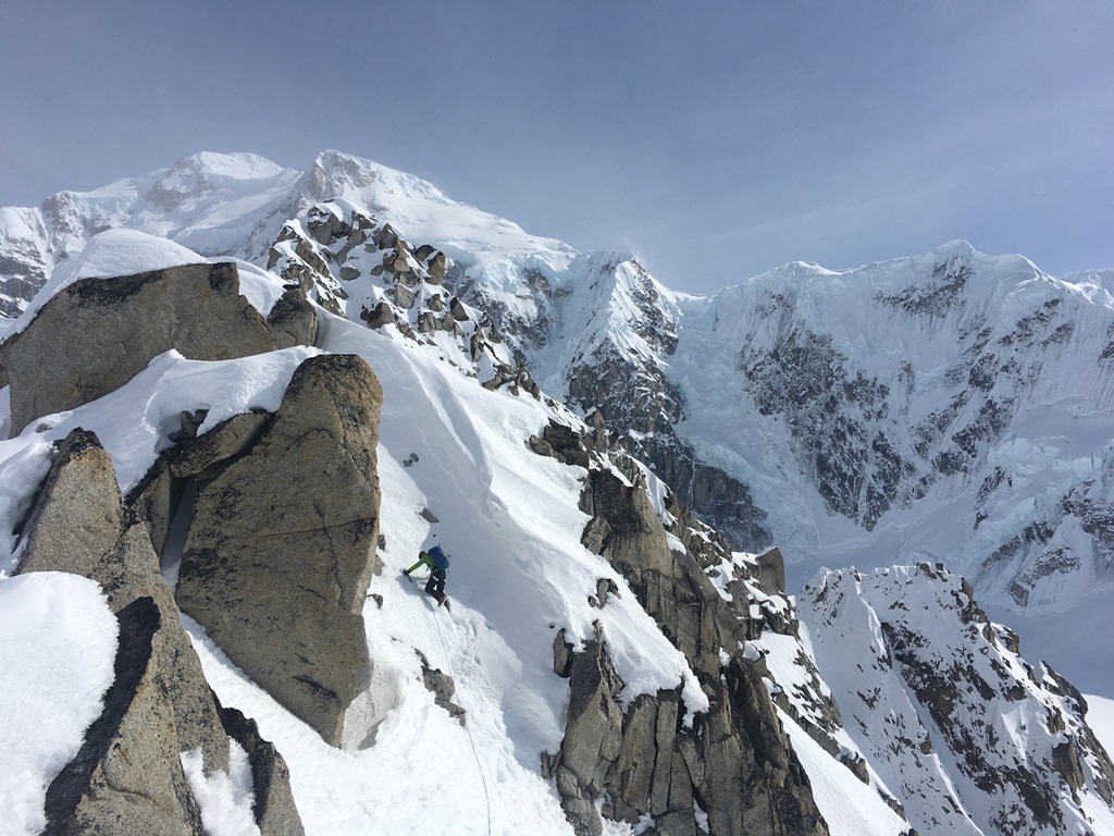 A roped mountaineer climbs a steep ridge