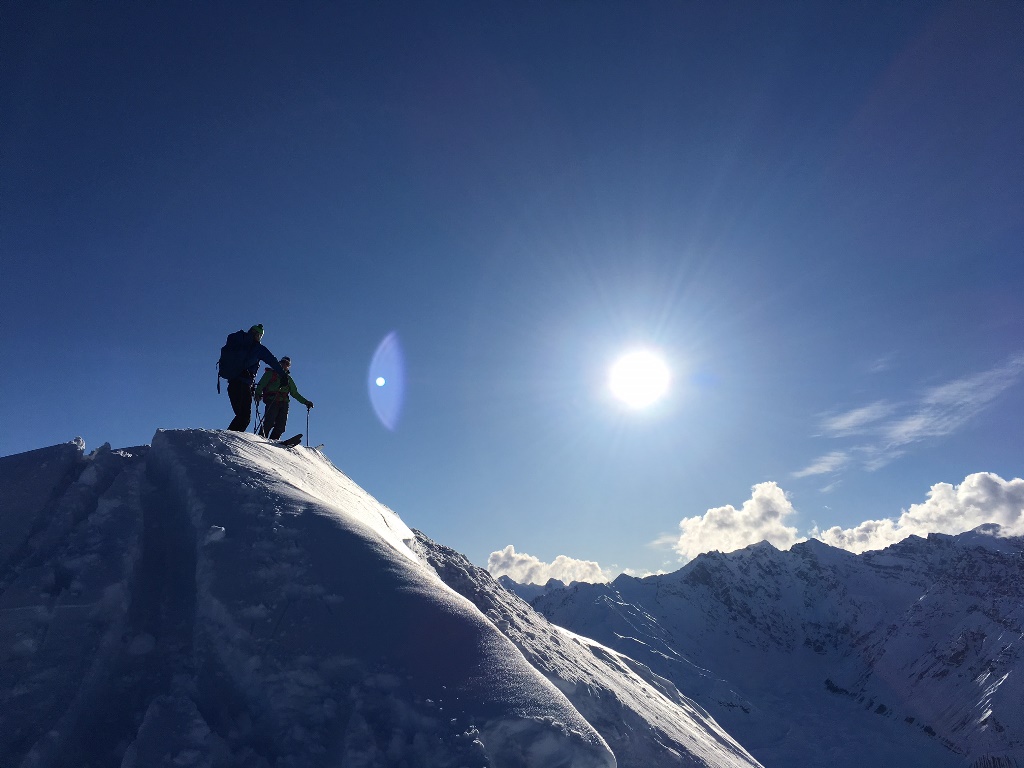 Two skiers in silhouette on top of a ridgeline