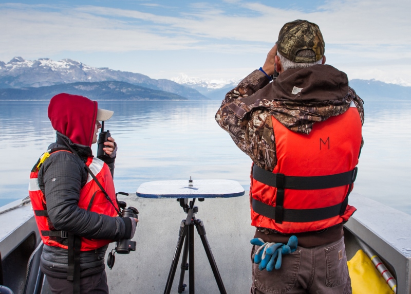 Researchers on a boat using binoculars