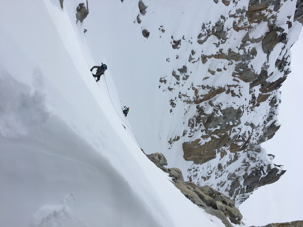 Two roped climbers ascend a steep snow ridge