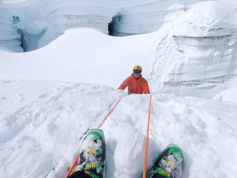 A climber smiles as he climbs out of a crevasse