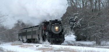 A steam locomotive pulls a passenger train during a winter excursion.  NPS Photo, Ken Ganz