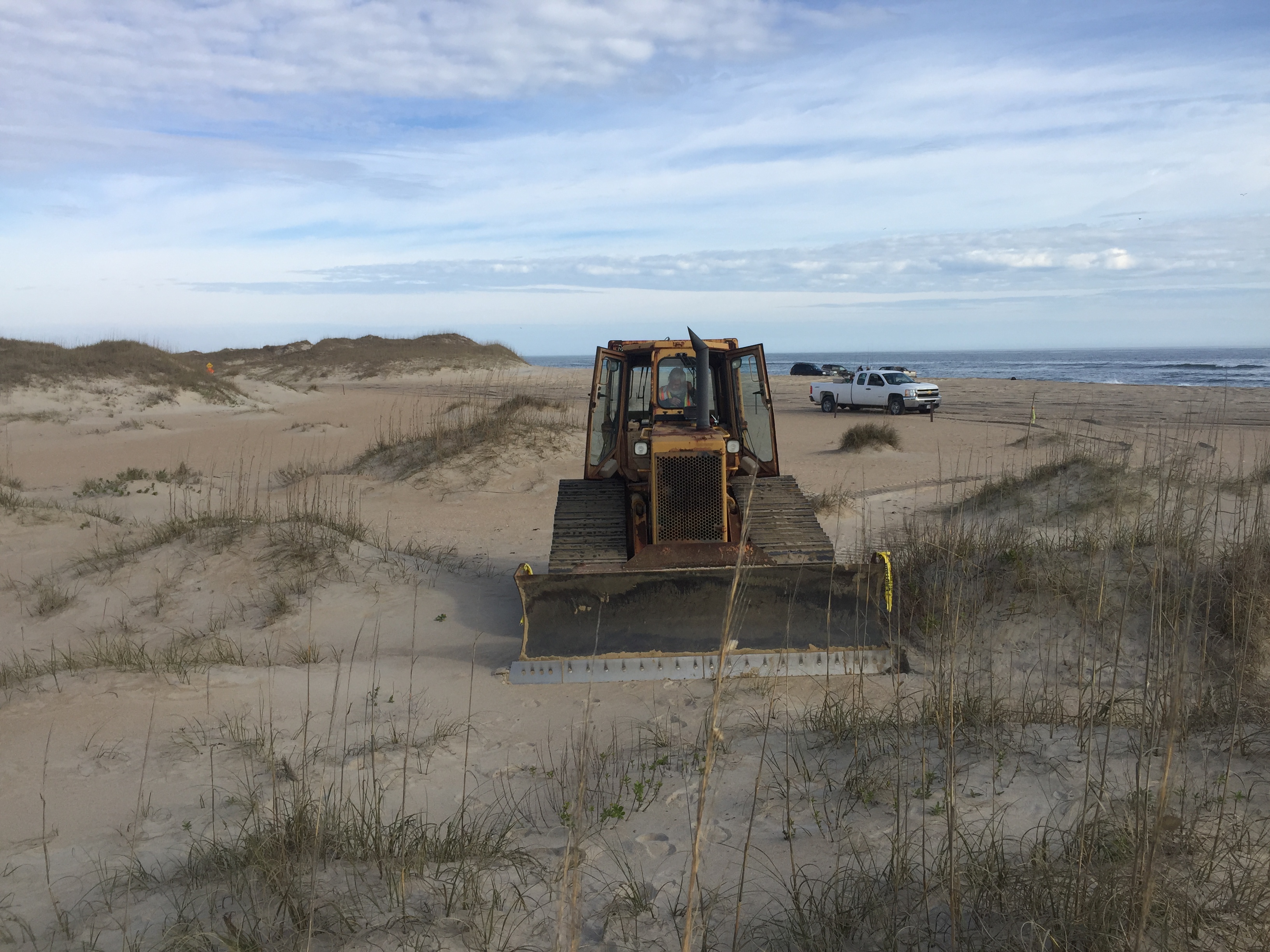 Bulldozer beginning work on Cape Point bypass extension. Park Ranger vehicle and Atlantic Ocean in background.