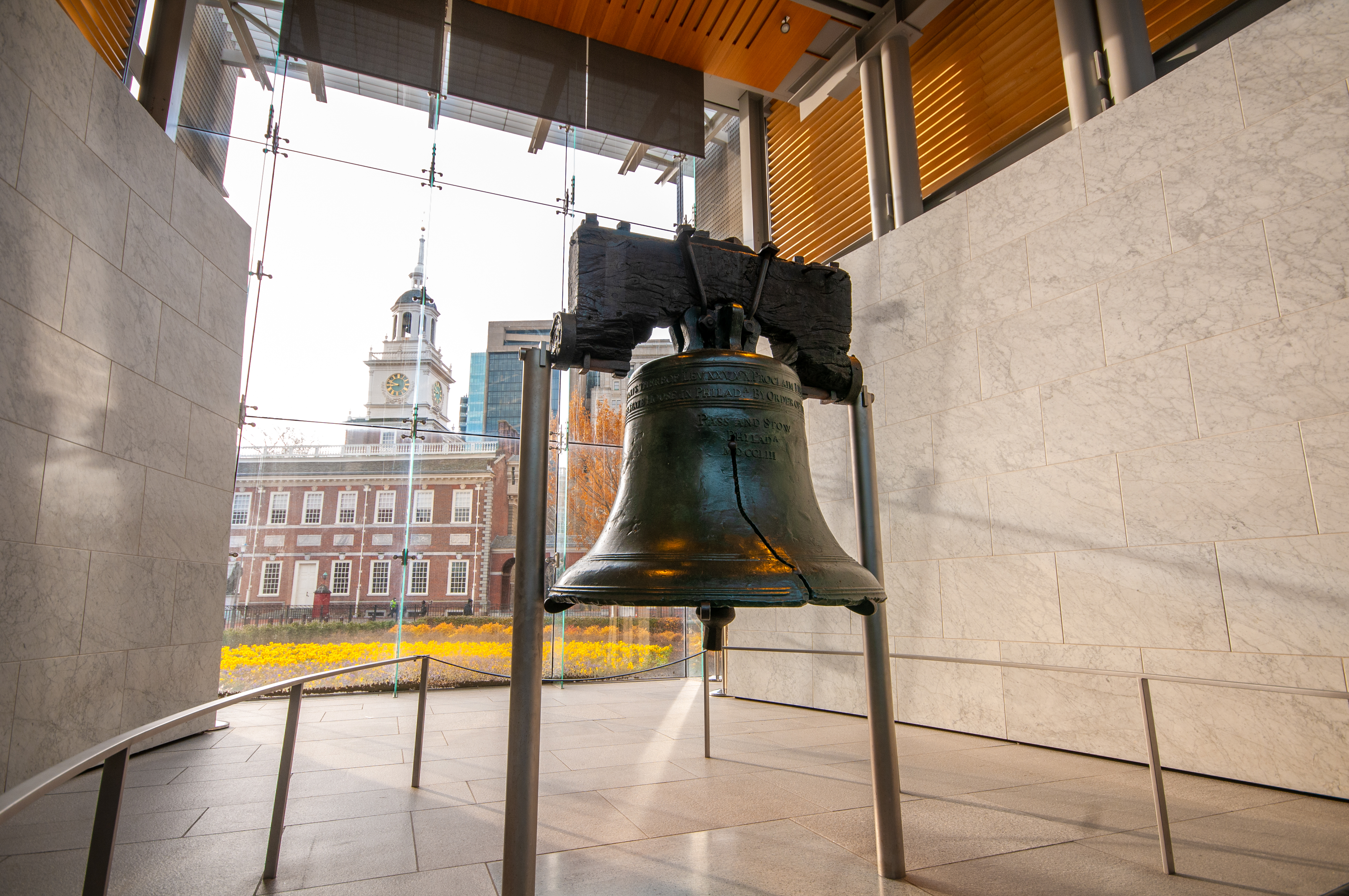 Color photo showing the Liberty Bell with Independence Hall in the background.