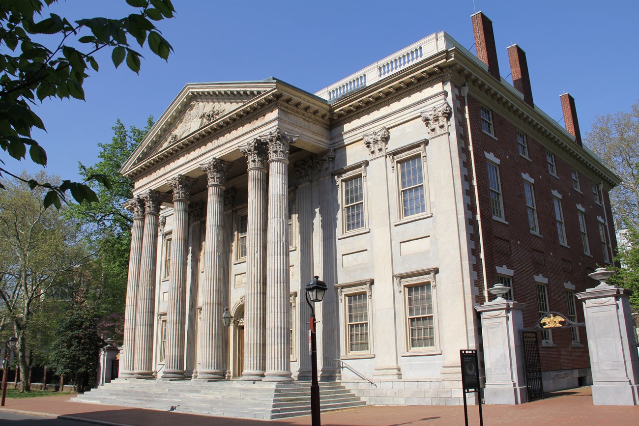 Two-story marble building with six columns and a pediment.