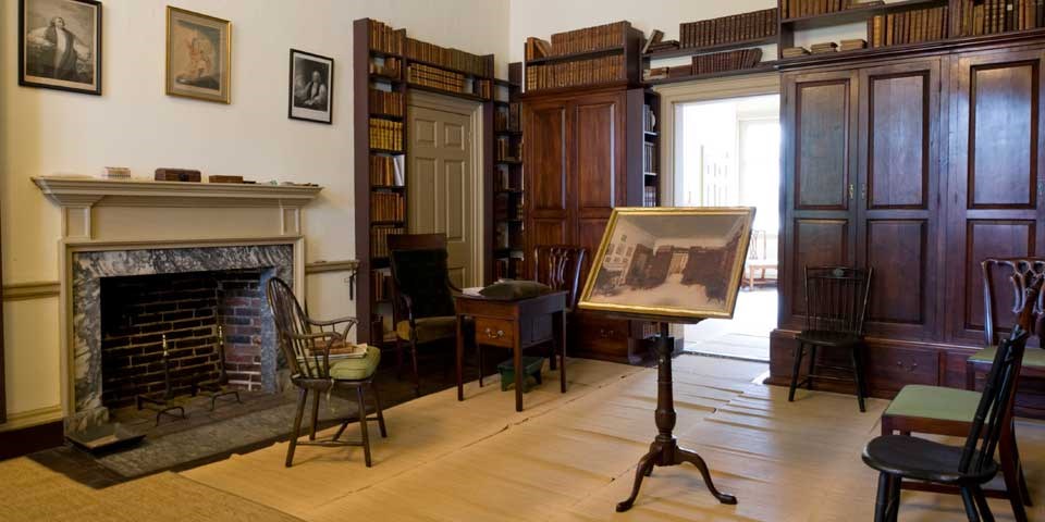 Color photo of room with bookcases along two walls, and early 19th century furnishings throughout the room.