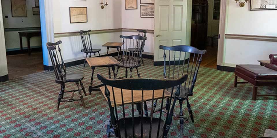 Room in City Tavern with groupings of Windsor chairs around a table.