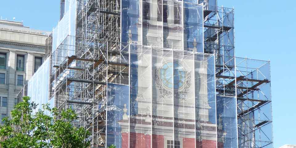 Detail of Independence Hall's tower, with scaffolding covered by a decorative fabric scrim made to look like Independence Hall's tower.