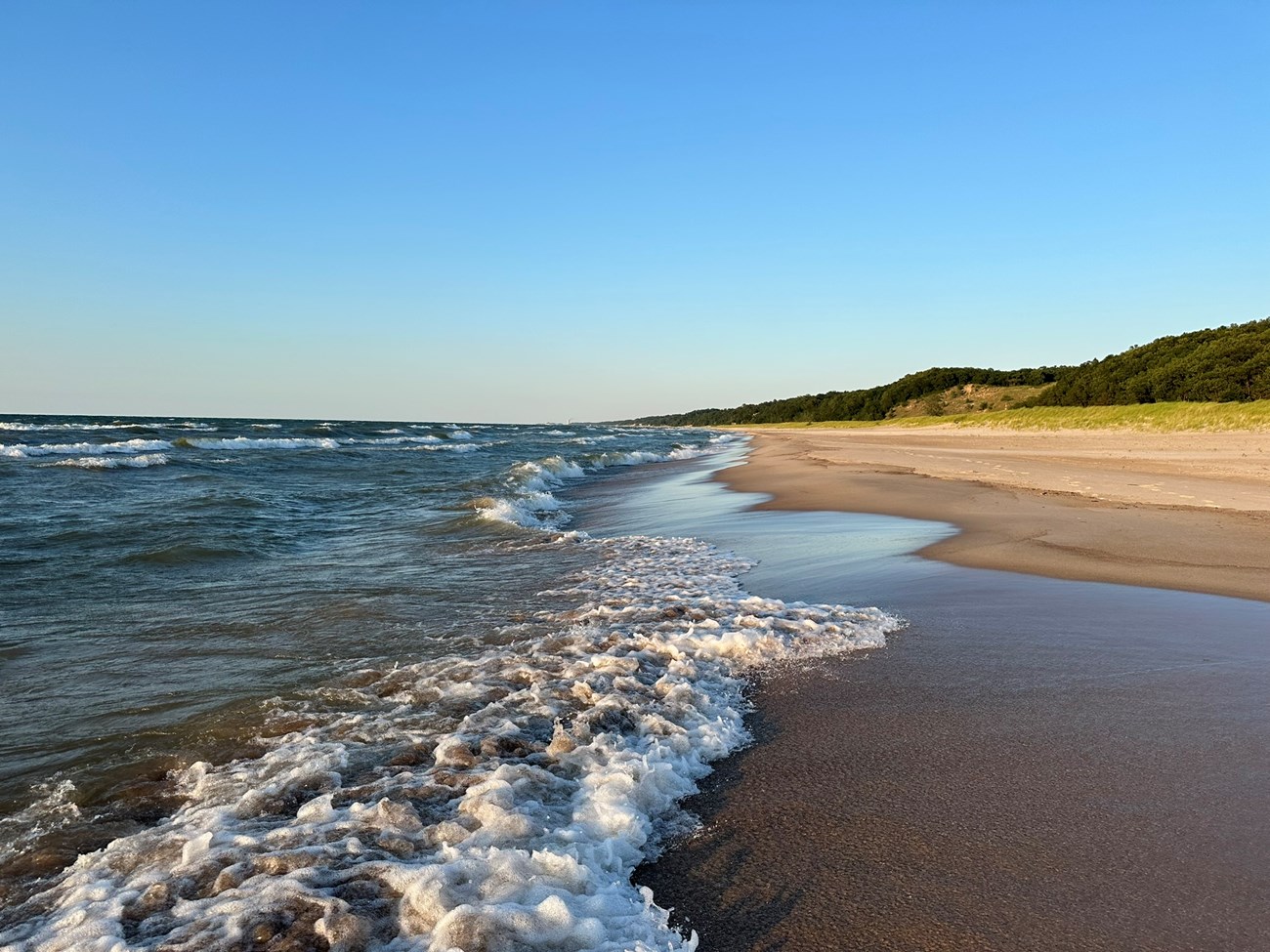 View looking down Lake Michigan's sandy beach on a bright summer day