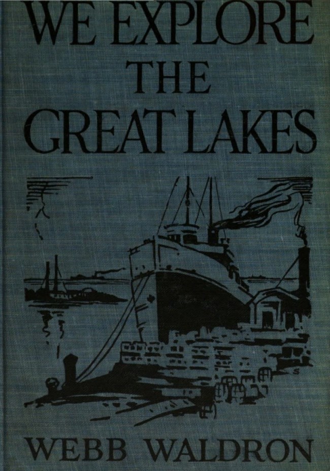 Blue cloth cover of 1923 book that reads the title "WE EXPLORE THE GREAT LAKES" at the top; separated from the bottom text that reads "WEBB WALDRON" with a black illustration of a large ship docking near a harbor of a town.