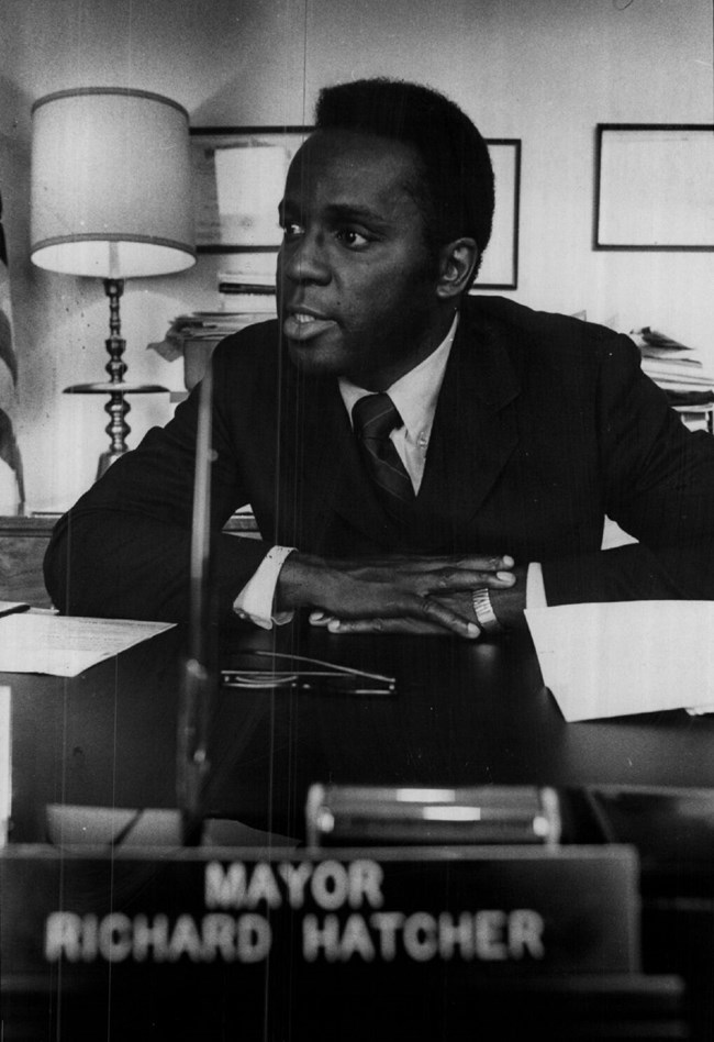 Gary's Mayor Richard Gordon Hatcher seated at his desk with a plaque bearing his name.