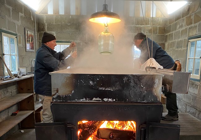 Two park volunteers tend syrup making in the Sugar Shack at the Chellberg Farm