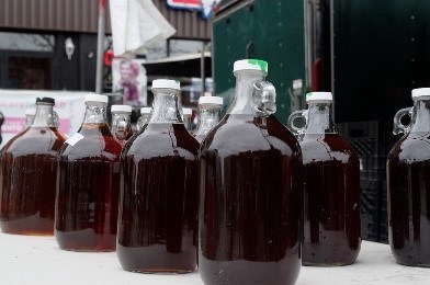 Glass gallon jars filled with dark, maple syrup.