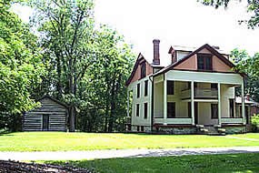 3 story building with large front porch surrounded by grass and trees in the background
