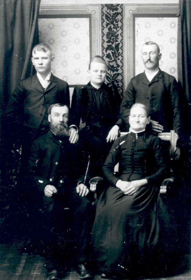 Chellberg family historic black and white portrait; 3 peoples standing and 2 are seated.