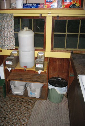 A drip water filtration system in the small kitchen of a cabin