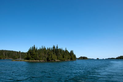 A scenic view of Tobin Harbor taken from a boat, blue sky, small island, blue water.
