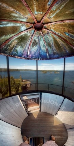 The view looking out onto a large lake from inside a lighthouse with glass windows