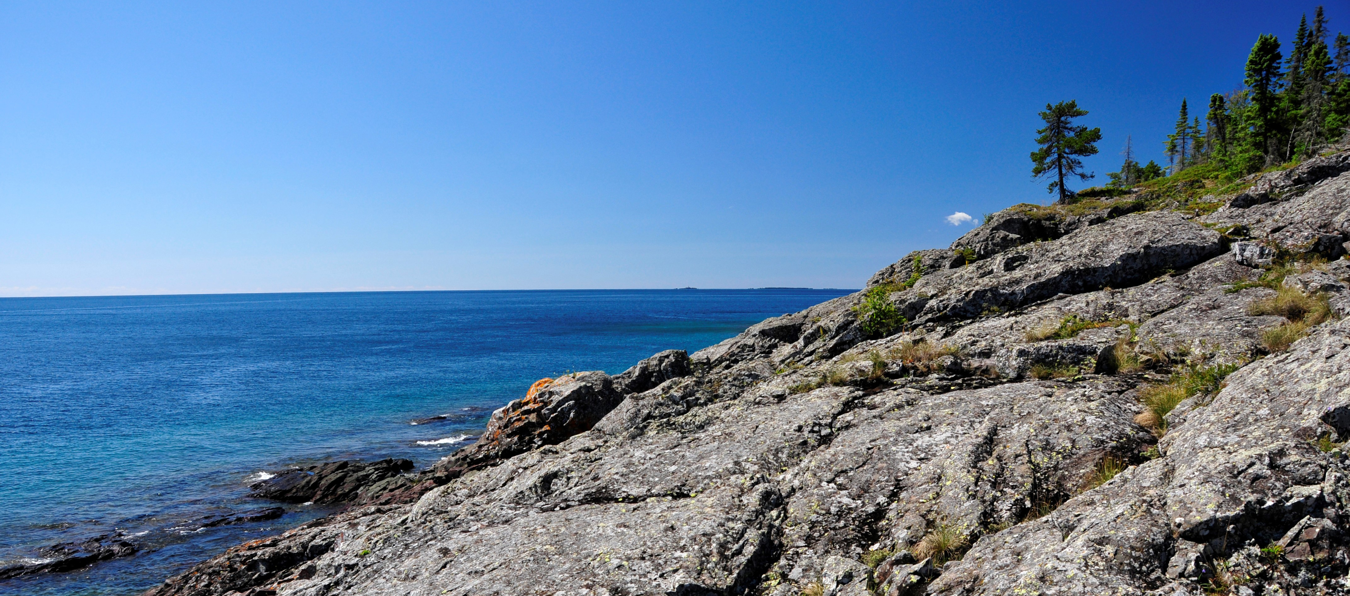 Sun shines down on a black, rocky shoreline.