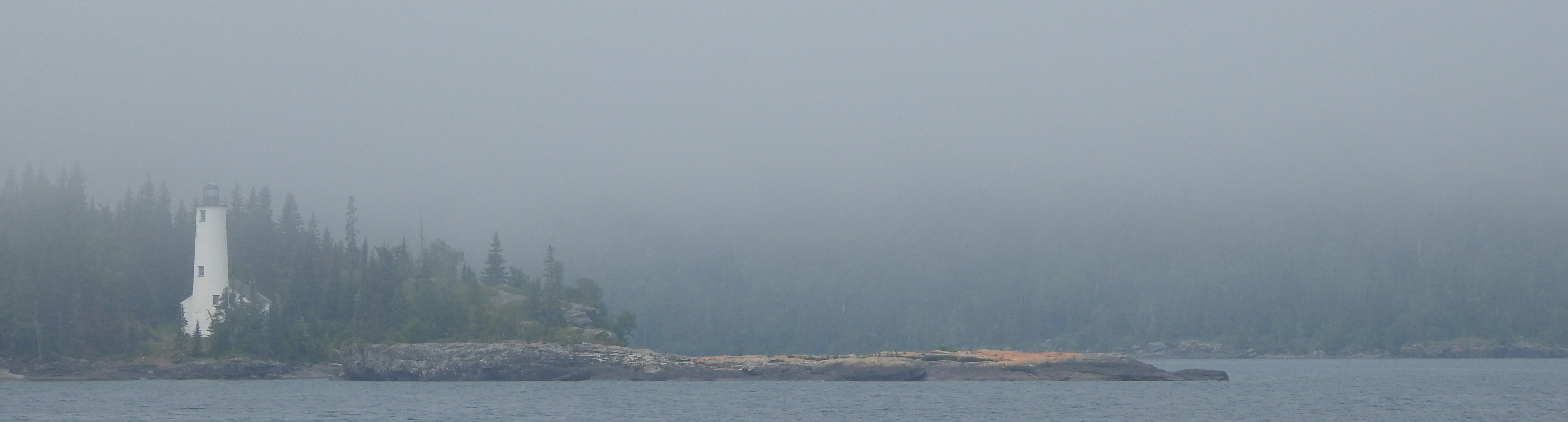 A tall white lighthouse in fog.