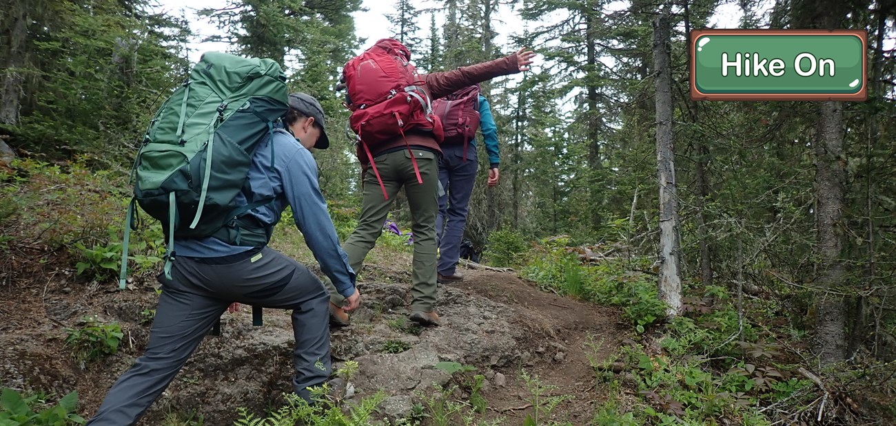 Three hikers wearing large backpacks walk over a small rock ridge with their arms out to keep balance.
