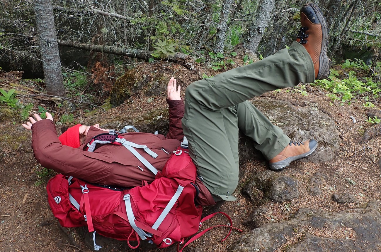 A person laying on their back on a trail after falling to the ground.