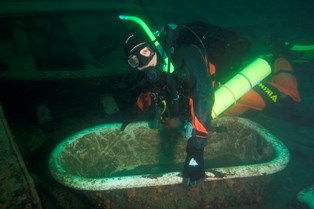 Diver poses with bathtub from the shipwreck Monarch.