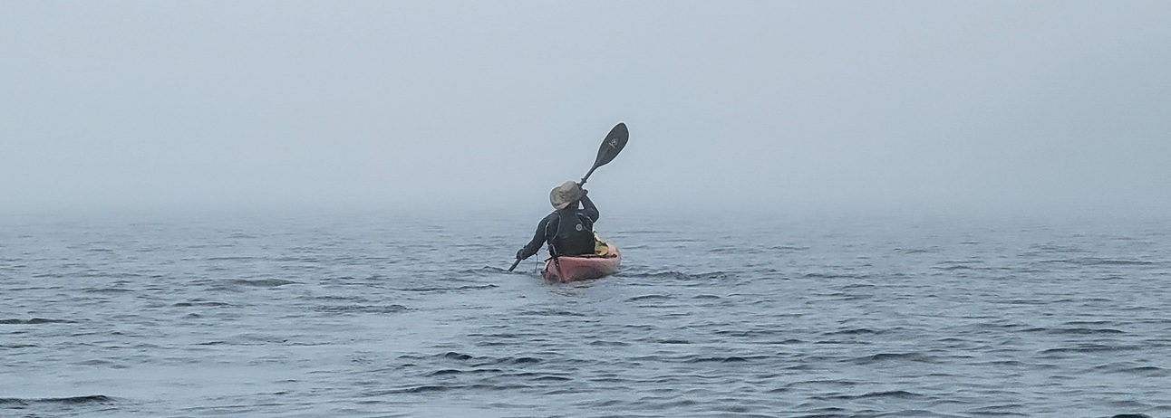 Kayaker is visible on the horizon despite dense fog on Lake Superior.