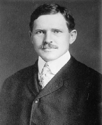 picture of a man with a mustache wearing a dark suit