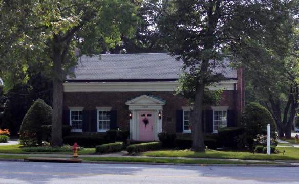 a small brick building with a pink door