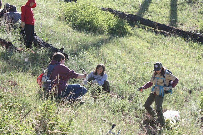 A group of youth kneel in on a grassy hill