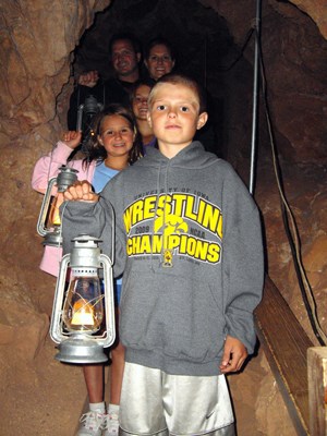 A family enjoys the Historic Lantern Tour route in Jewel Cave.  This tour is offered only during the summer months.
