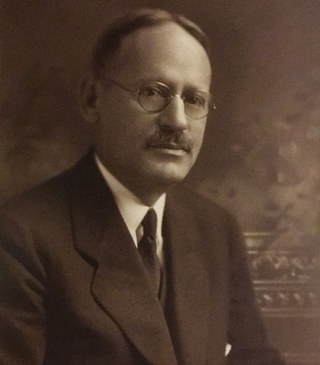 Portrait photograph of an older white man (Albert P. Greensfelder) wearing spectacles, a mustache, and dark suit and tie.