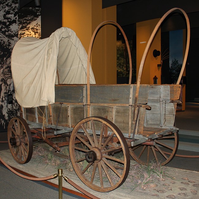 An old wagon, partially covered with a white canvas