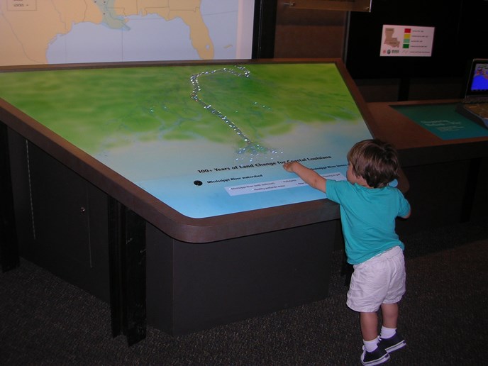 Image of a little boy looking at an exhibit about the Mississippi River and its deltas