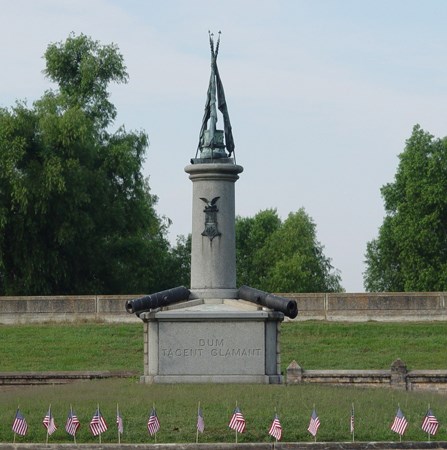 Image of Civil War-era memorial with crossed rifles at top and row of small American flags in front