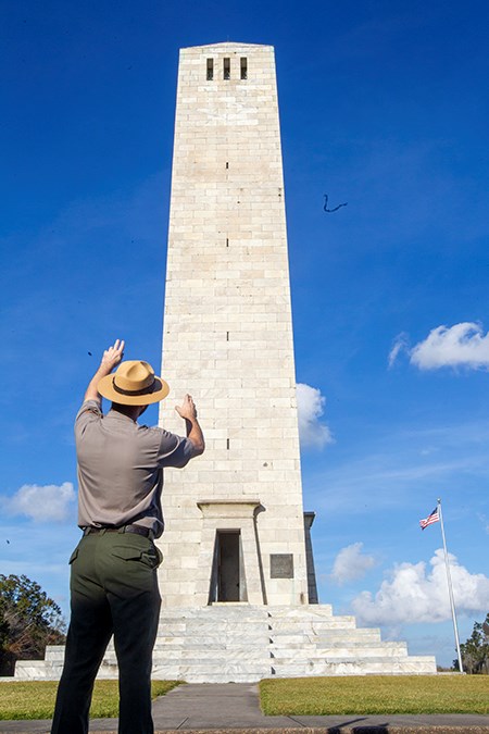 ranger with back turned to us pointing to chalmette monument