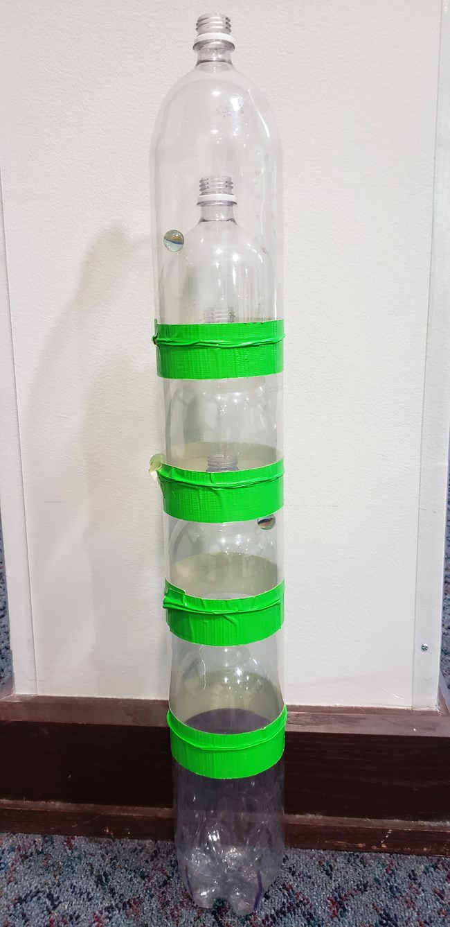 clear soda bottles nested cut open and nested within each other. taped with green tape.
