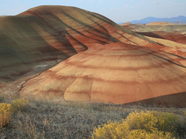 Photograph of the painted hills, weathered rocky hills with alternating tan and rust colored layers.