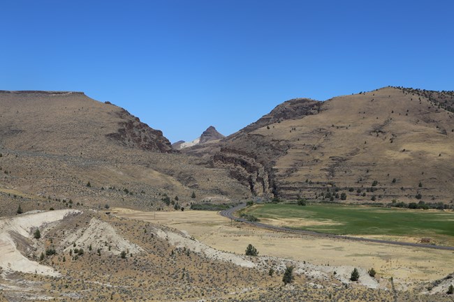 A cut through a mountain, dark jagged rocks at the edges. A road weaves through the gap.