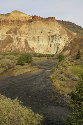 A river is in the foreground with a colorful cliff in the background.